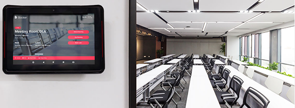 A tablet affixed to the wall outside a meeting room which lets you book rooms and check room availability using Booker